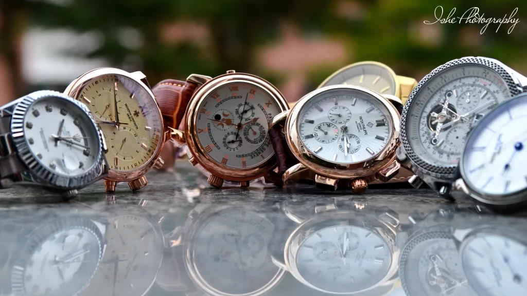 An assortment of luxury timepieces, each showcasing unique, intricate detailing and richly-colored watch faces set in polished gold and silver casings.